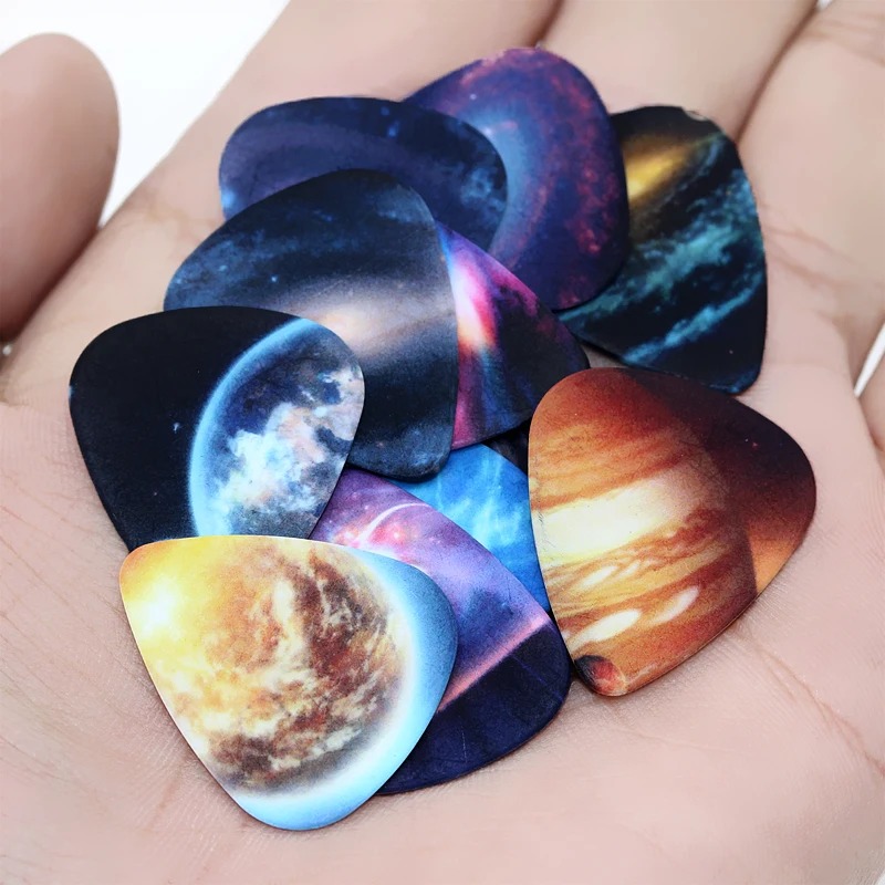 Vista completa del set di 10 plettri con motivi Universo, Spazio, Pianeta e stelle