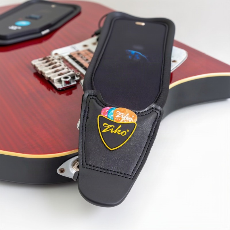 Extrémité en simili cuir surpiqué et écusson jaune de la sangle Fusion Foudre posée sur une guitare électrique