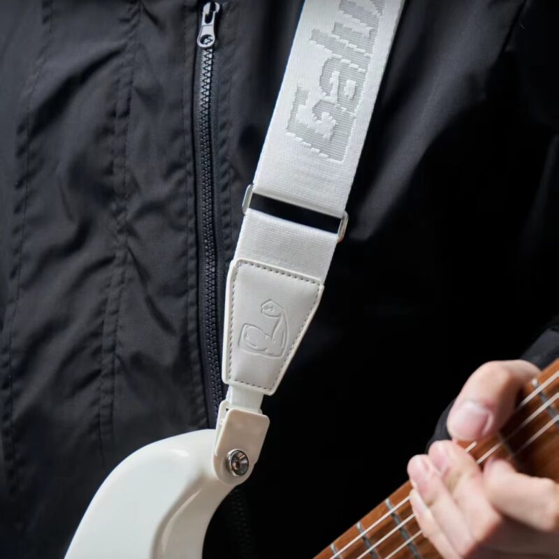 Guitariste portant la sangle Power Grip blanche sur une guitare électrique blanche